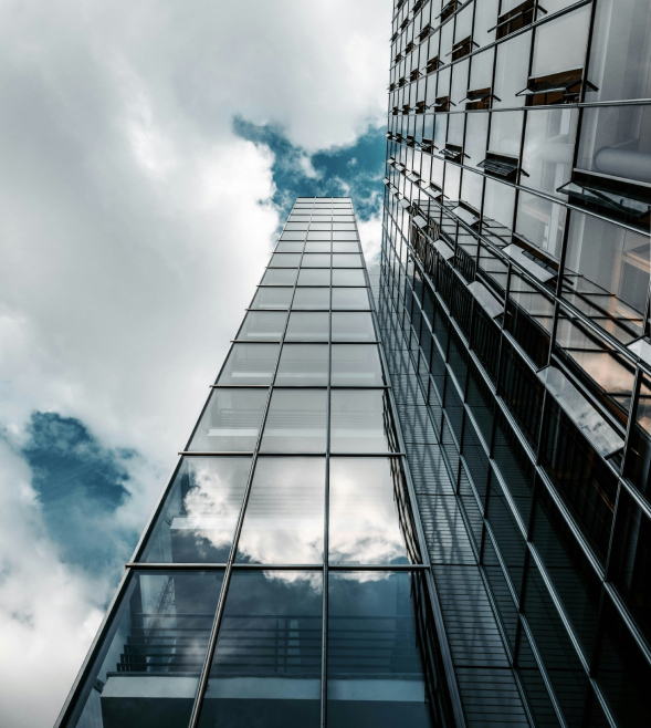 looking upward next to high rise with partially cloudy sky above