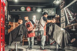 Two men get their beards trimmed at a small business barber. How much is small business general liability insurance?