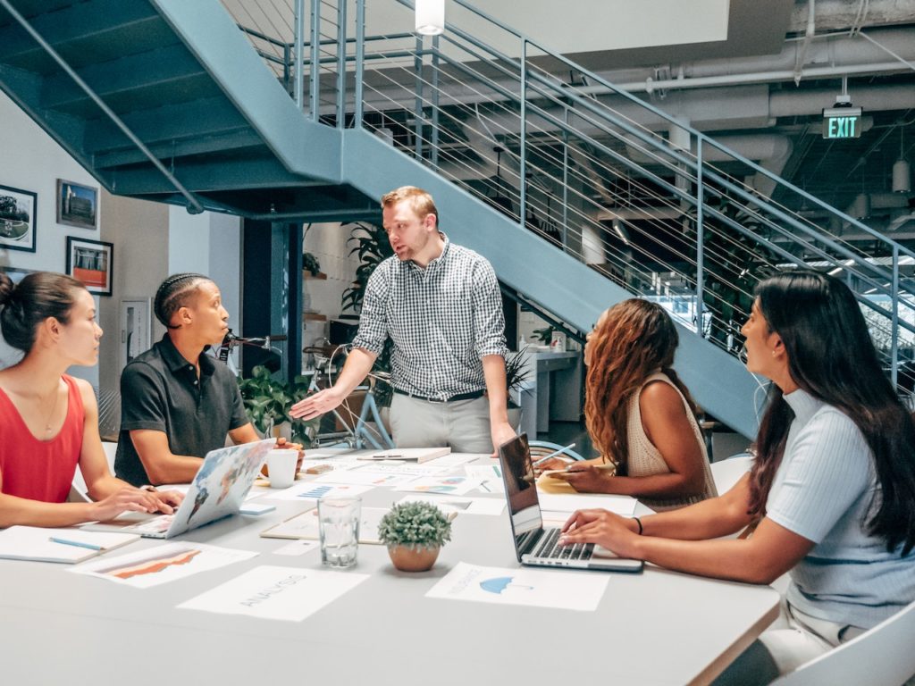 A group of diverse business men and women sit around a table discussing strategy. What is EPLI Insurance?